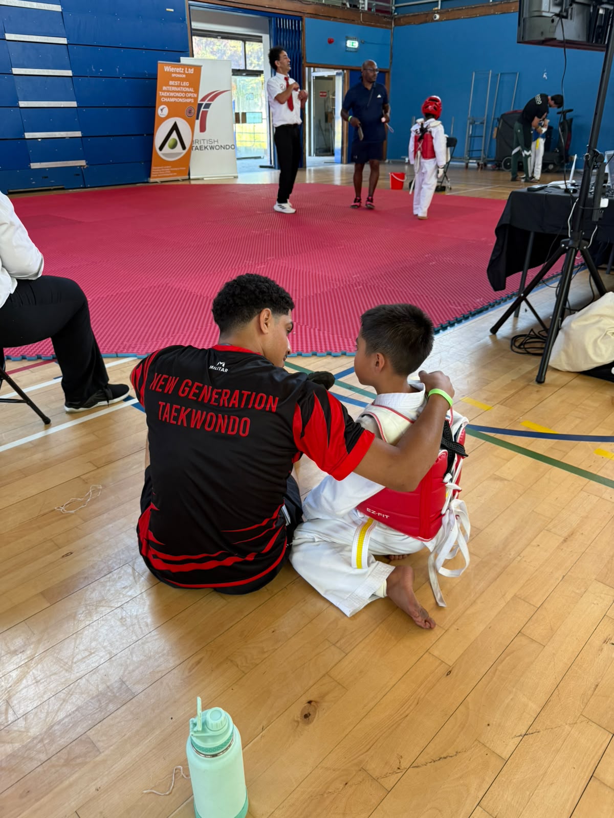 Coach supporting a young athlete after a taekwondo match