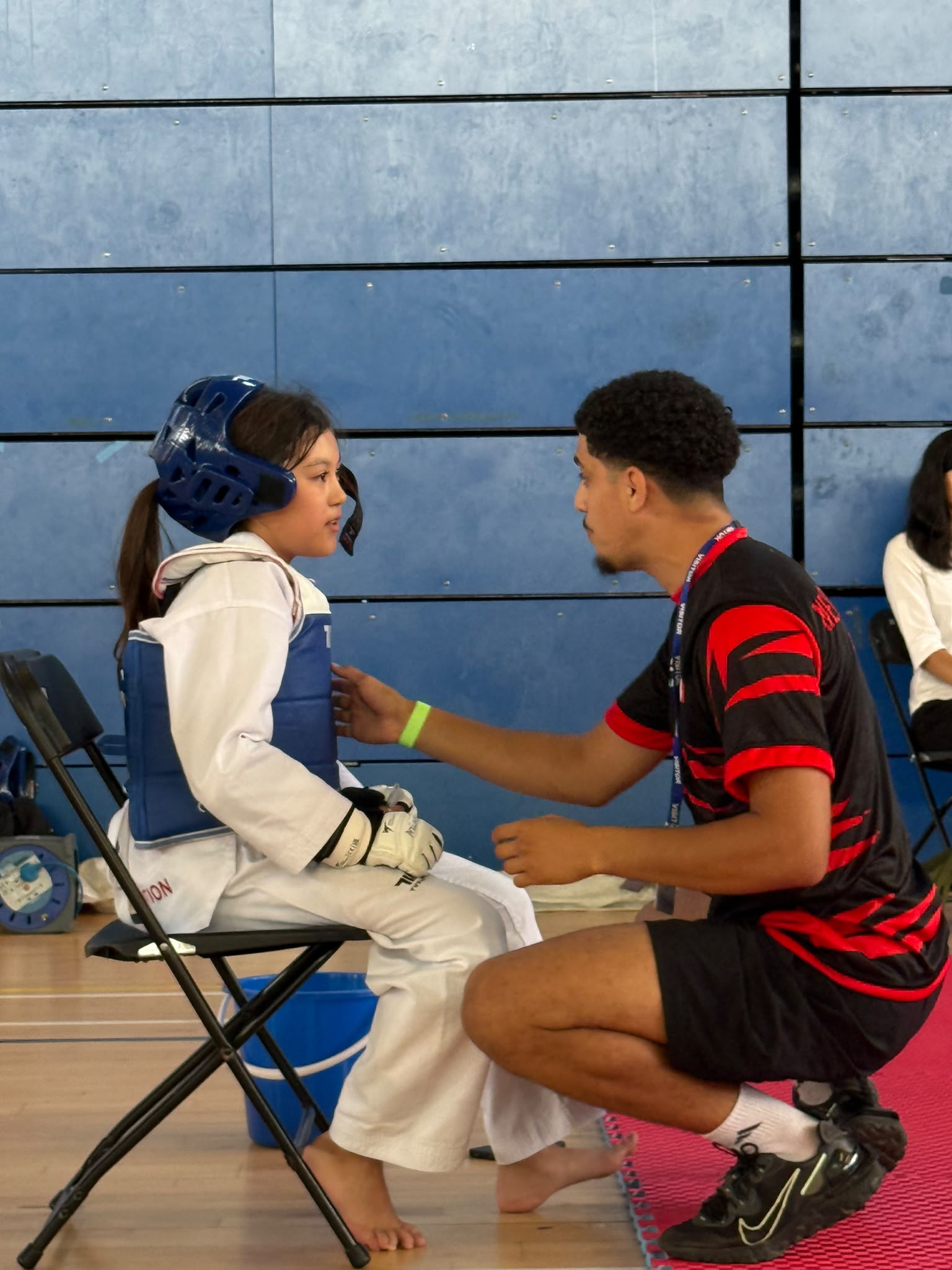 Coach giving tactical guidance to a young taekwondo athlete at a competition