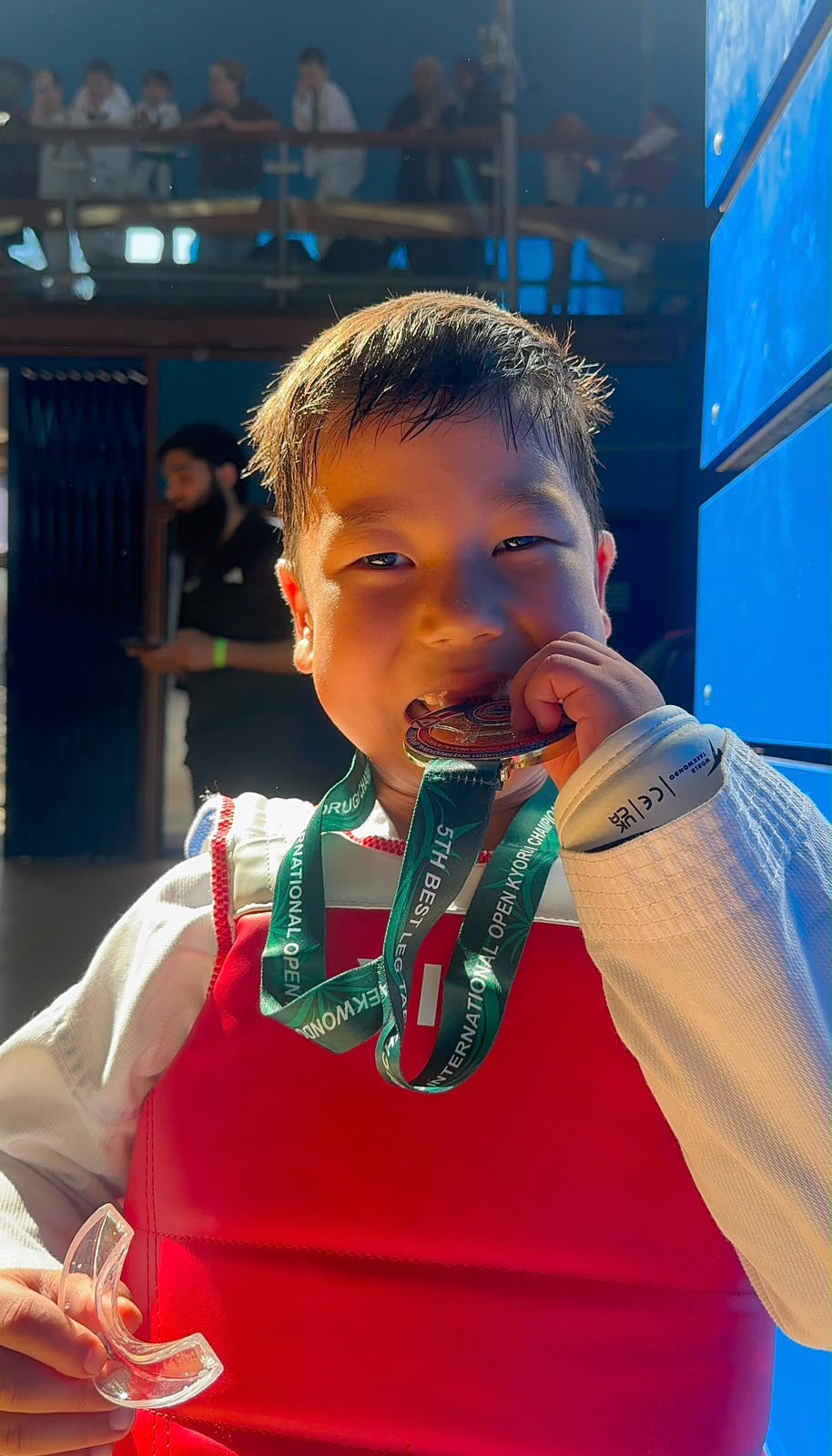 Young New Generation Taekwondo athlete smiling with a gold medal at a competition
